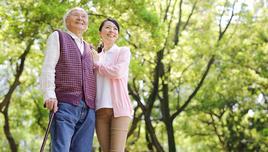 Companion caregiver walking outdoors with a happy senior client