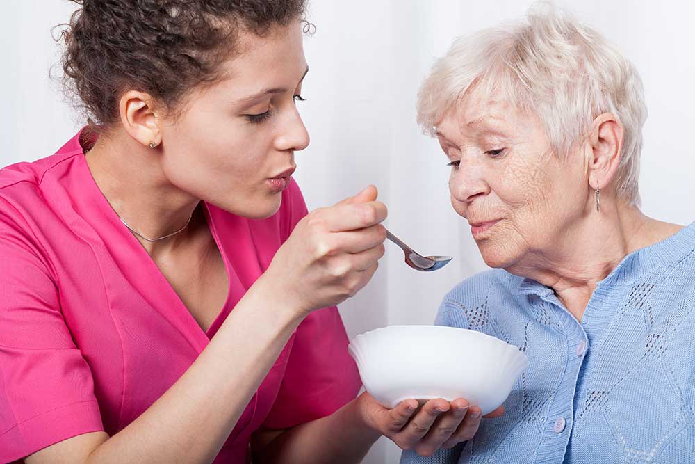 Caregiver assisting a senior woman with her meal
