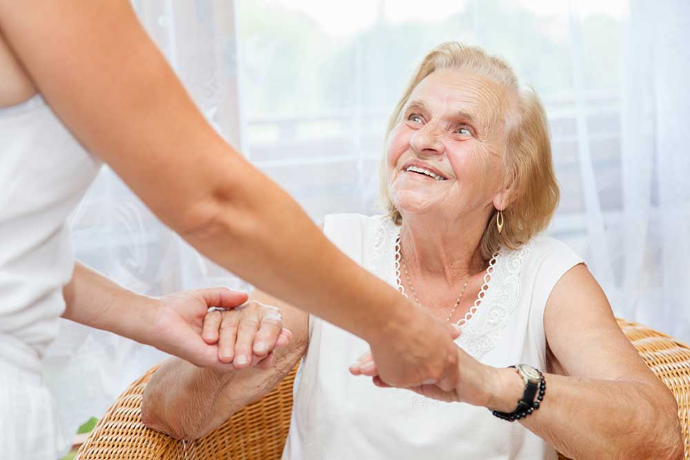 Personal care aide comforting an elderly woman at home