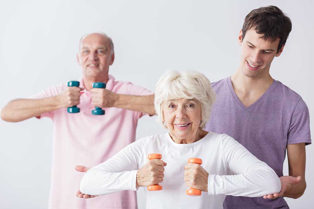 Home health aide encouraging seniors during light exercise